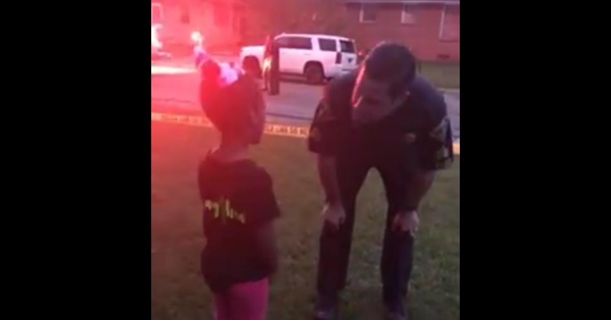 police officer bent over talking to little girl.