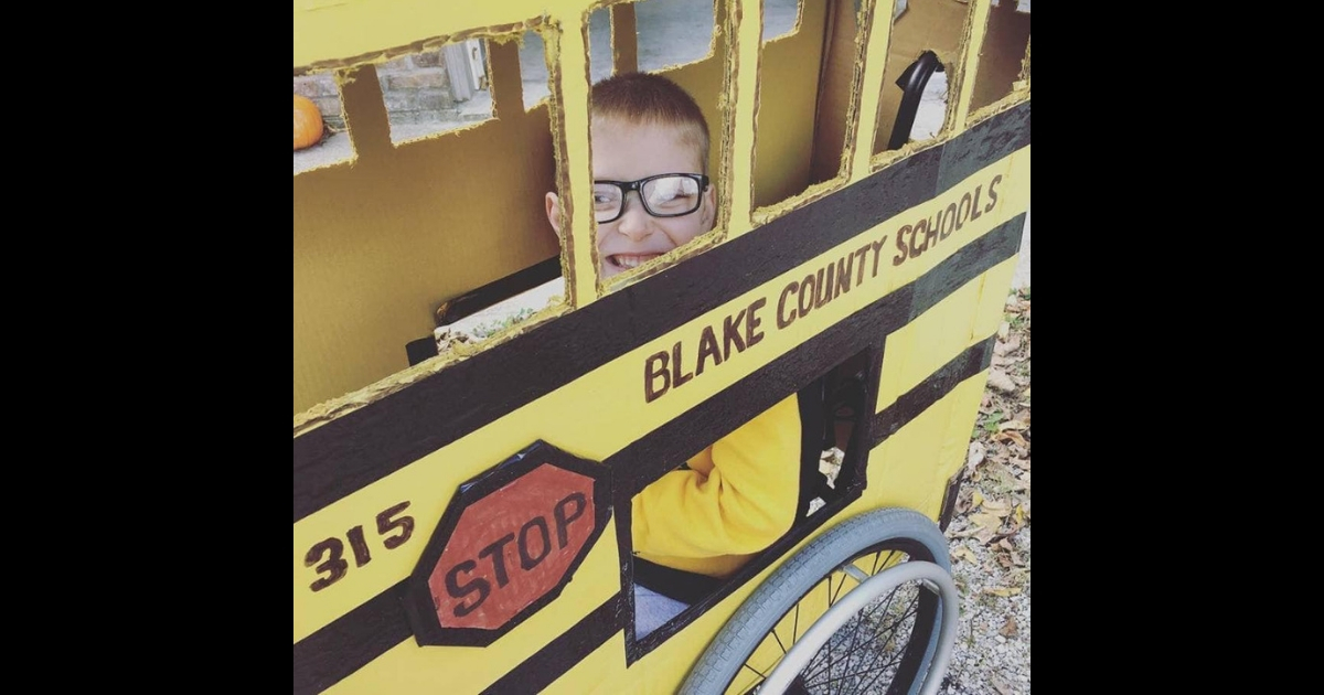 A little boy confined to a wheelchair with a school bus custom made costume.