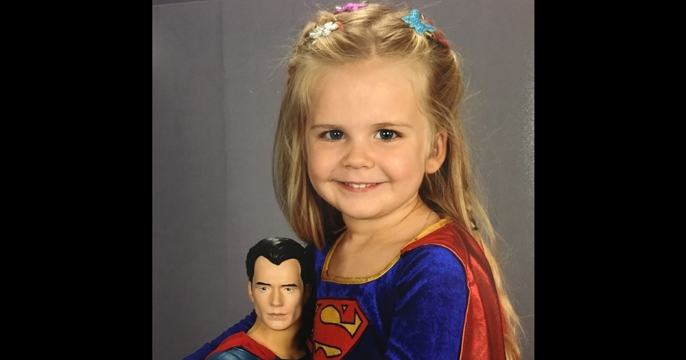 Little Girl wears Superman costume for school pictures.
