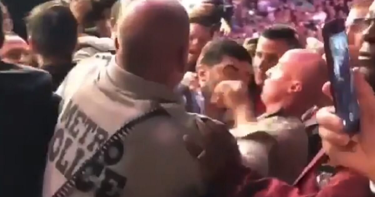 A police officer struggles to separate fighters during the melee that broke out Saturday after an Ultimate Fighting Championship bout between Russian Khabib Nurmagomedov and Irishman Conor McGregor.