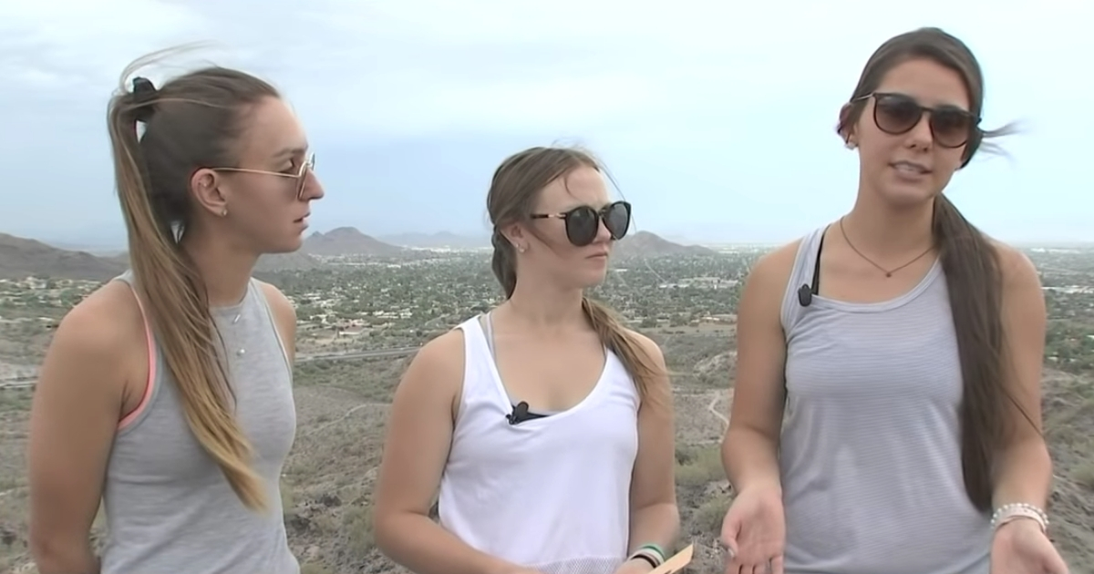 Three girls are interviewed on top of a mountain.