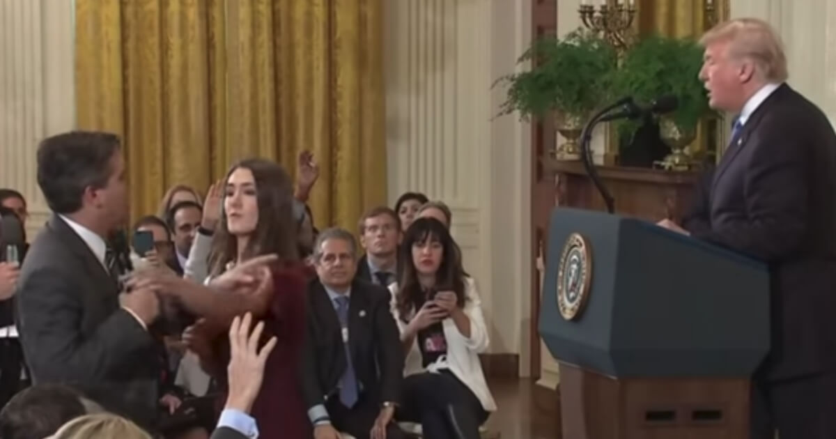 CNN's Jim Acosta, far left, tries to prevent a White House aide from taking a microphone from him during a press briefing at the White House on Wednesday.