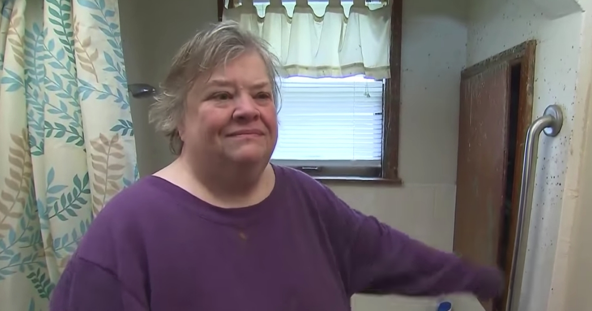 A woman stands in front of a bathtub that held her captive.