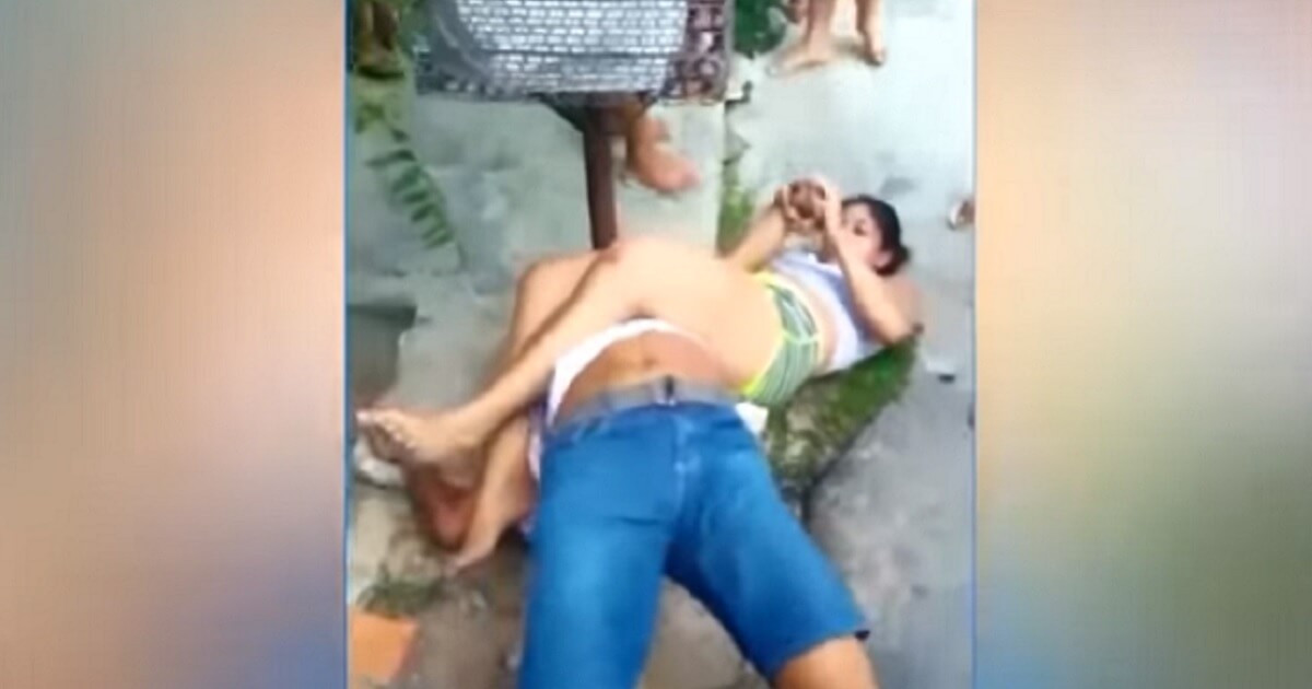 Woman and man scuffle on ground.