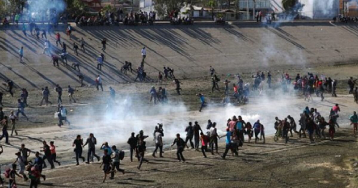 Tear gas drifts among fleeing migrants.