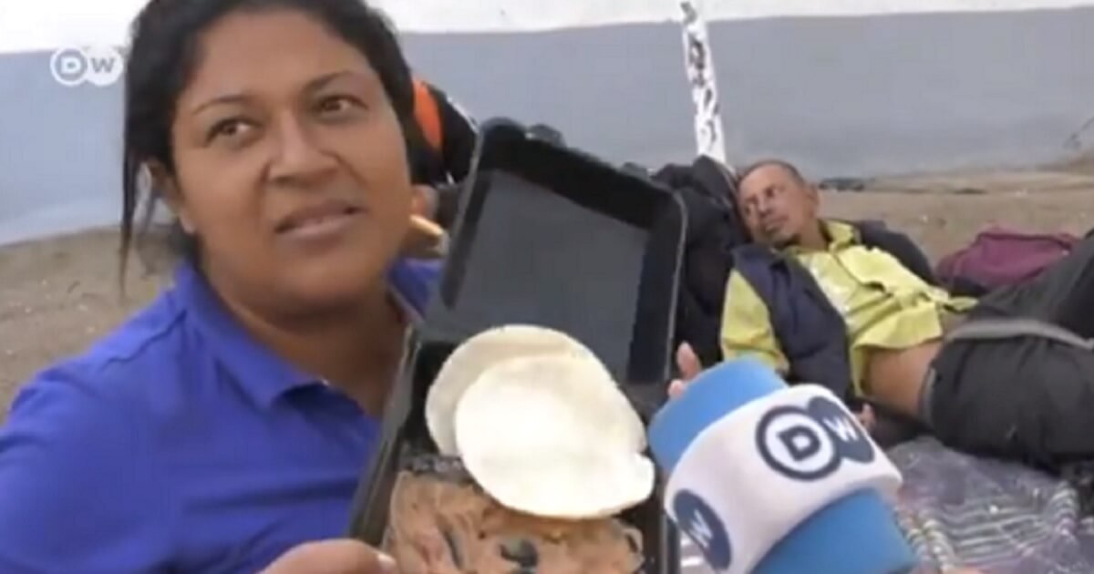 Woman in caravan camp holding plate of refried beans.