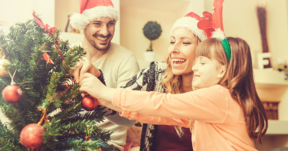 A happy family decorating a Christmas tree in the living room.