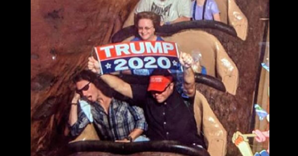 Man holds "Trump 2020" sign aboard the Splash Mountain ride in Disney World.