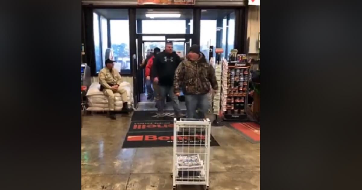 An orderlly line of shoppers enters a gun store.