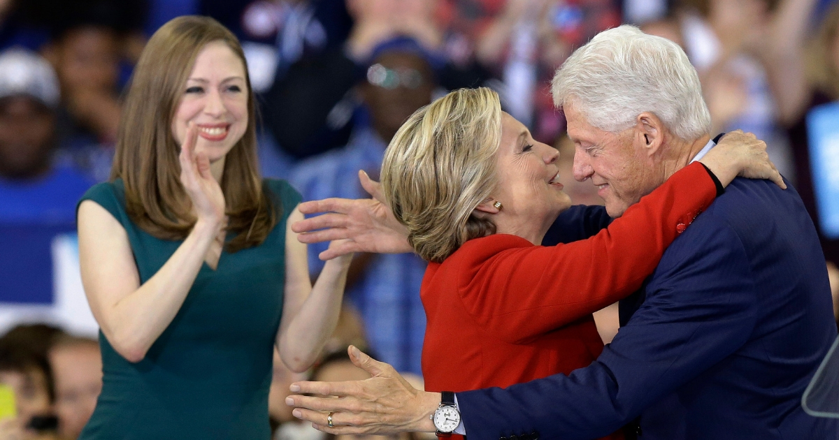 Democratic presidential candidate Hillary Clinton hugs her husband, former President Bill Clinton as their daughter Chelsea Clinton looks on during a campaign rally.
