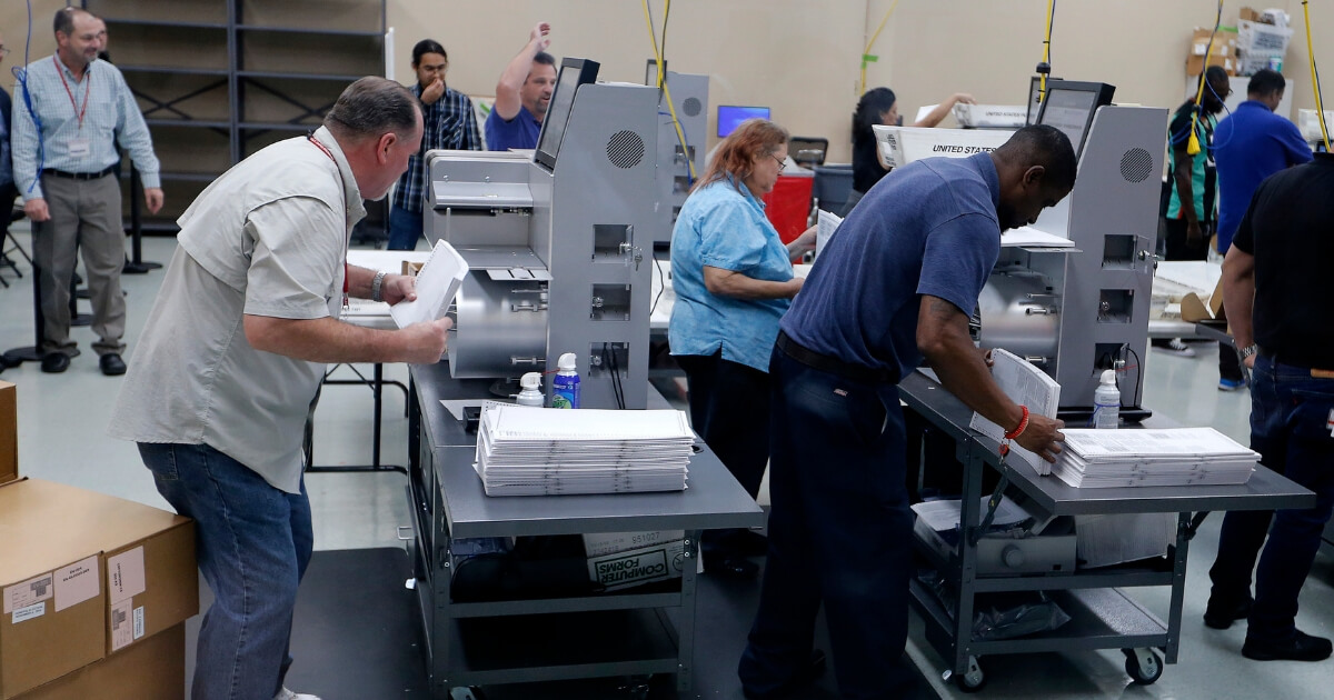 Elections staff load ballots into machine as recounting begins at the Broward County Supervisor of Elections Office on Nov. 11, 2018, in Lauderhill, Florida.