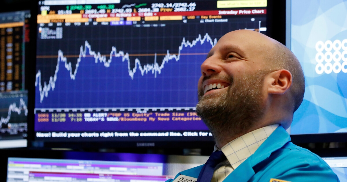 A trader smiles as he works on the floor of the New York Stock Exchange