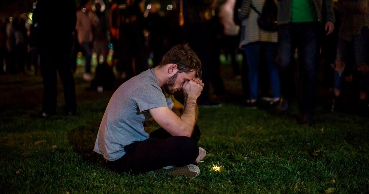 A man rests his head on his hands during a vigil to pay tribute to the victims of a shooting in Thousand Oaks, California