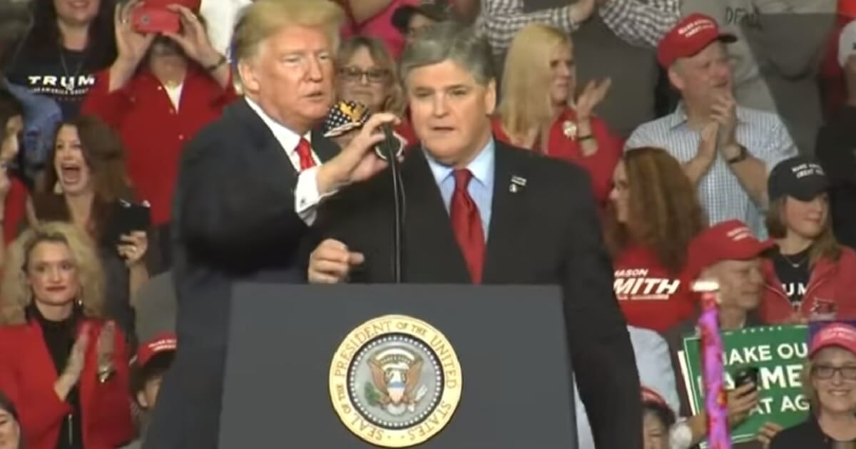 President Donald Trump adjusts the microphone for Fox News host Sean Hannity as Hannity makes an unexpected visit to the stage in Missouri on Monday during Trump's final rally before before Tuesday's midterms.