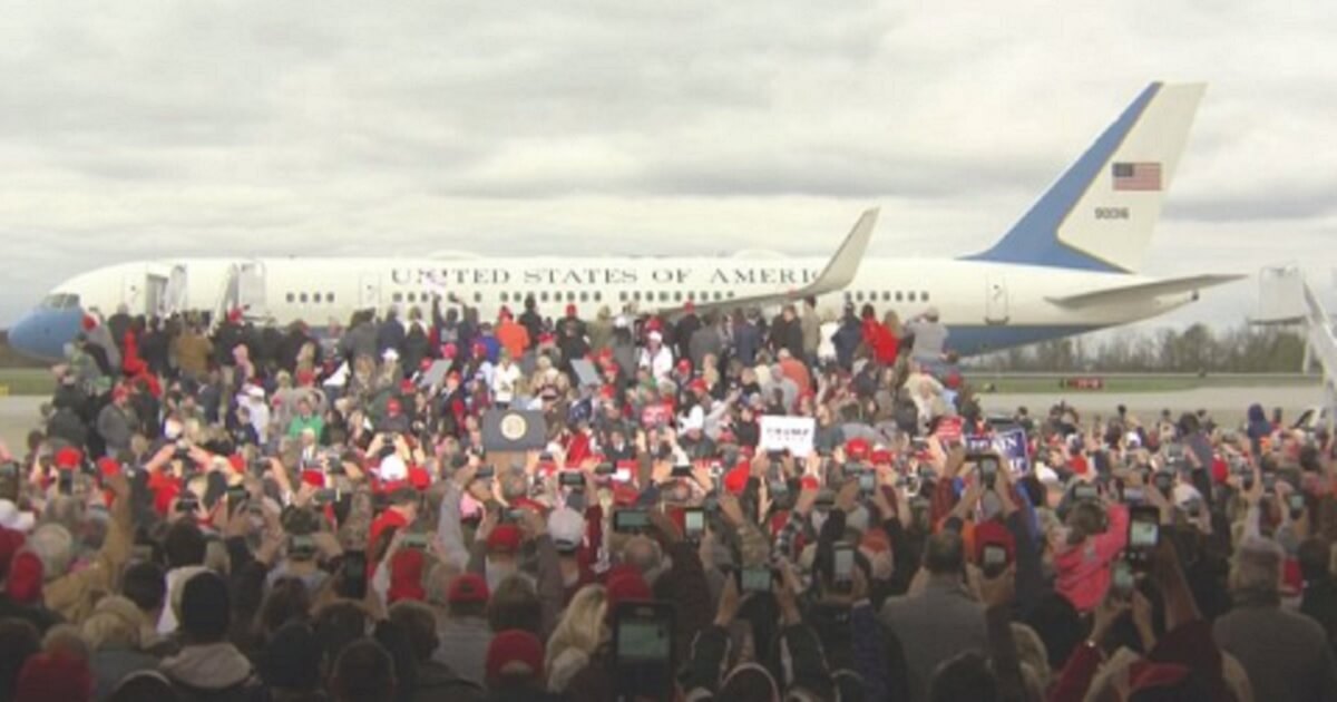 A crowd of Trump supporters with Air Force One in the background.