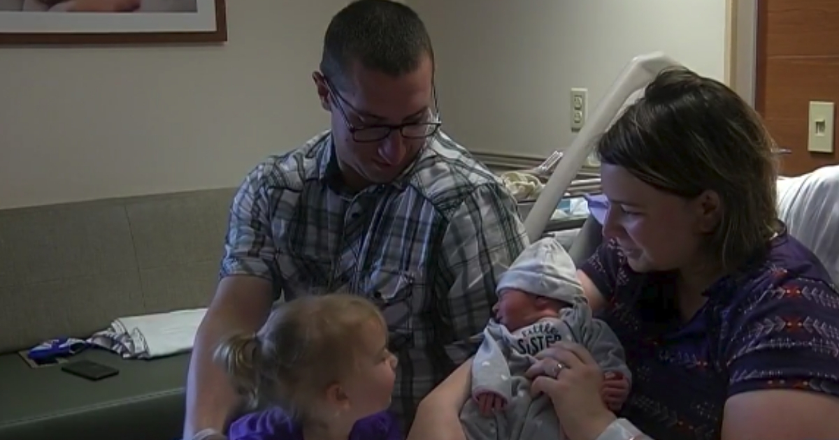 A family of four looks at the newborn in the hospital.