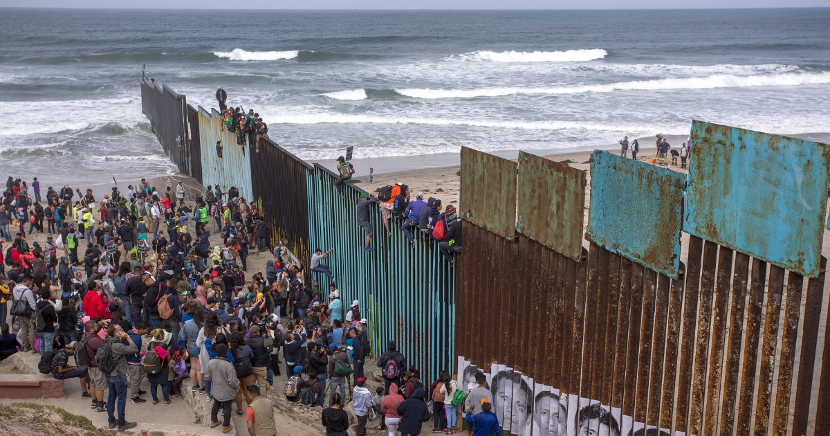 People climb a section of border fence to look into the U.S. as members of a caravan of Central American asylum seekers arrive to a rally on April 29, 2018, in Tijuana, Baja California Norte, Mexico.