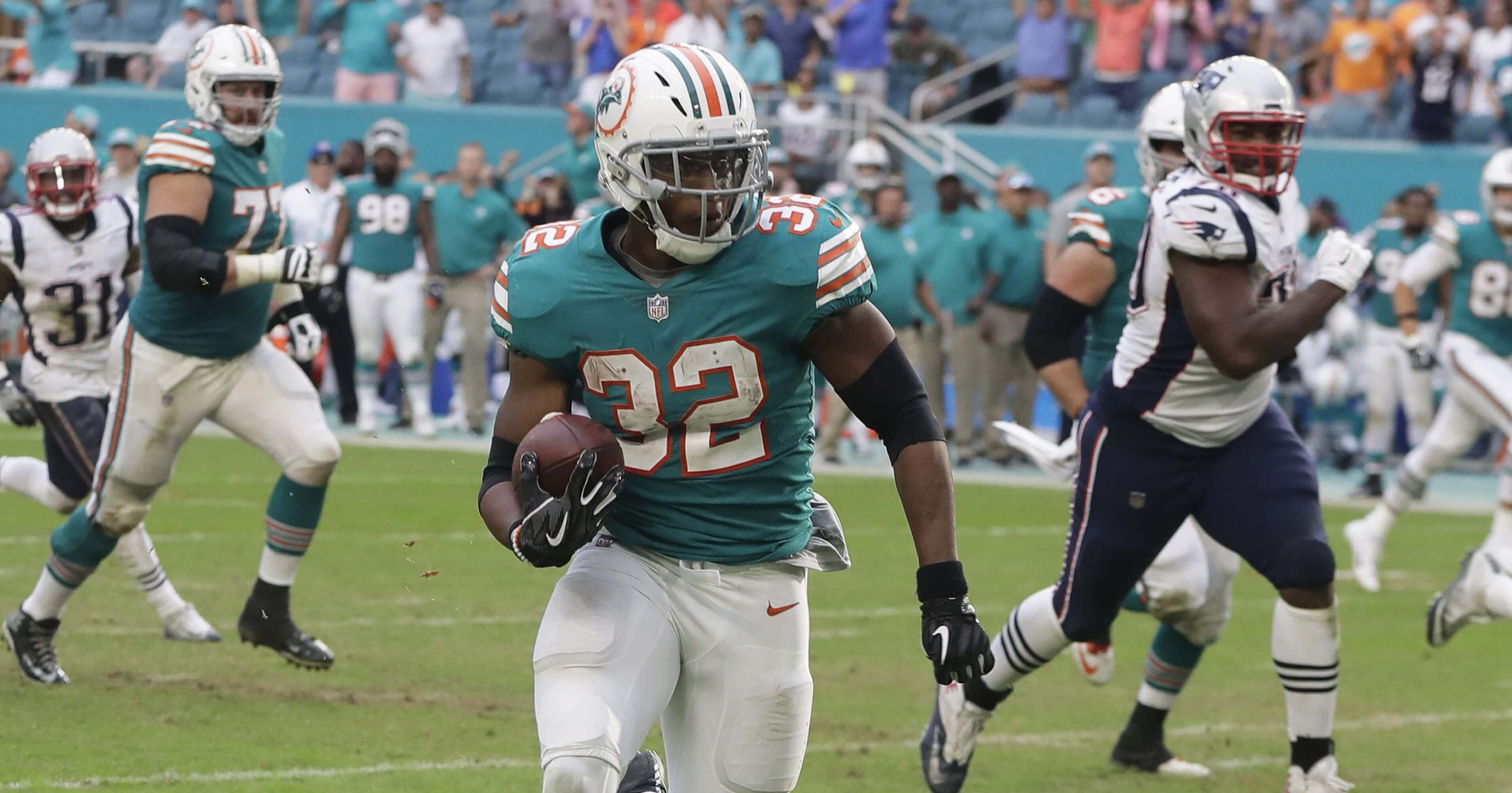 Miami Dolphins running back Kenyan Drake (32) runs for a touchdown in the final seconds to stun the New England Patriots on Sunday in Miami Gardens.