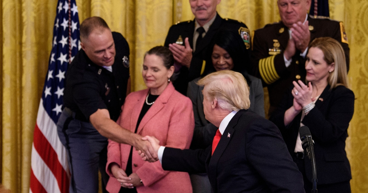 US President Donald Trump shakes the hand of Nebraska State Trooper Sam Mortensen during an event on a year of progress and action to combat the opioid crisis.