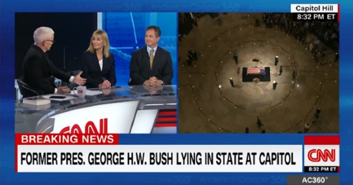 Anderson Cooper and his panel juxtaposed with the image of former President George H.W. Bush's coffin lying in state in the Capitol rotunda.