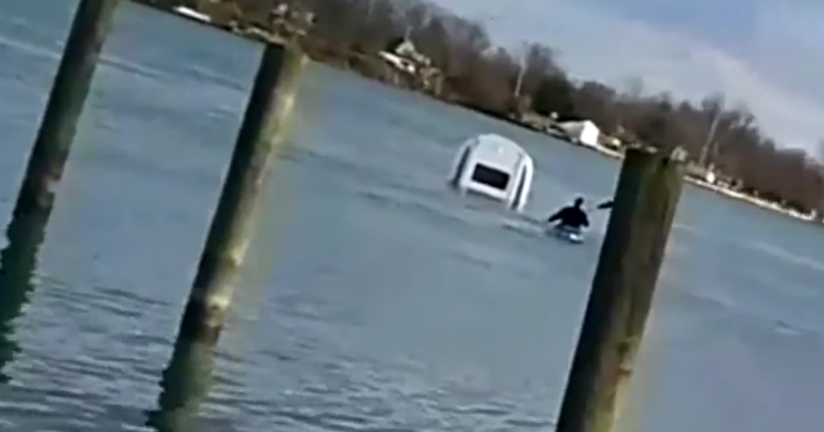 Car sinking and police paddling out to it.