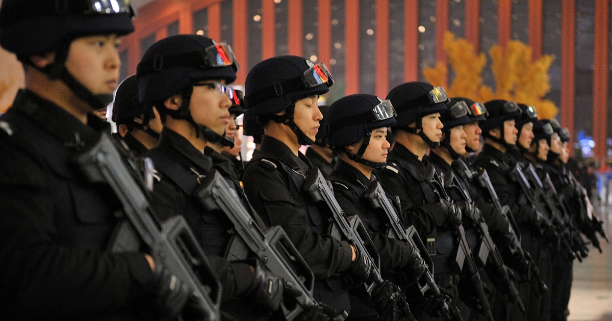 Police stand guard as Chinese telecom fraud suspects, deported from Guangzhou, are escorted off a train after arriving at the Harbin west station Jan. 15, 2018.