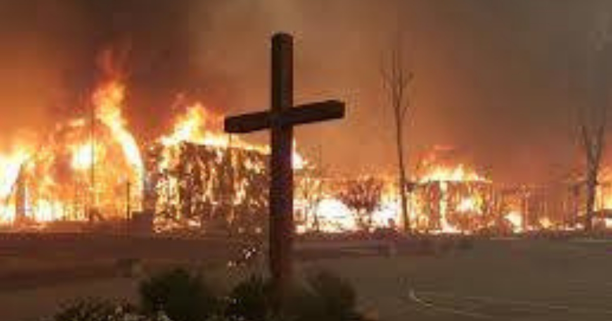 A wooden cross stands during a raging fire.
