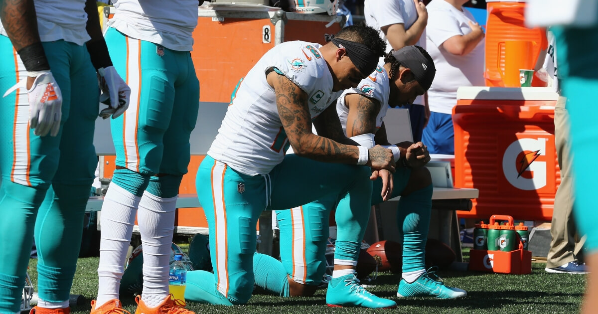 Kenny Stills, left, and Albert Wilson of the Miami Dolphins kneel during the national anthem prior to their game against the New England Patriots at Gillette Stadium on Sept. 30.