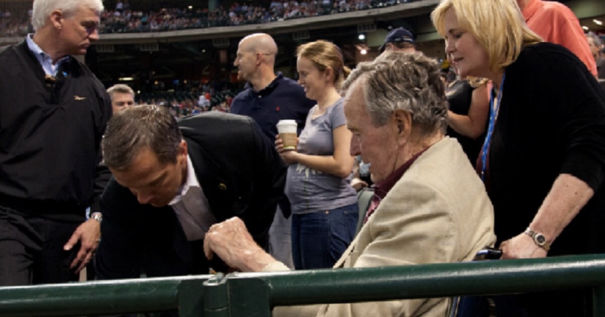 Former President George H.W. Bush is assisted by a Secret Service agent at a Houston Astros game at Minute Maid Park in Houston in 2011.