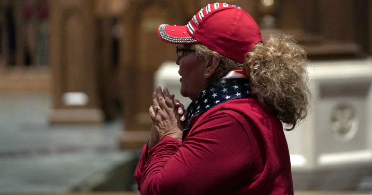 A woman clasps her hands inside Houston's St. Martin's Epicopal Church after former President George H.W. Bush's remains arrived at the church on Wednesday night.