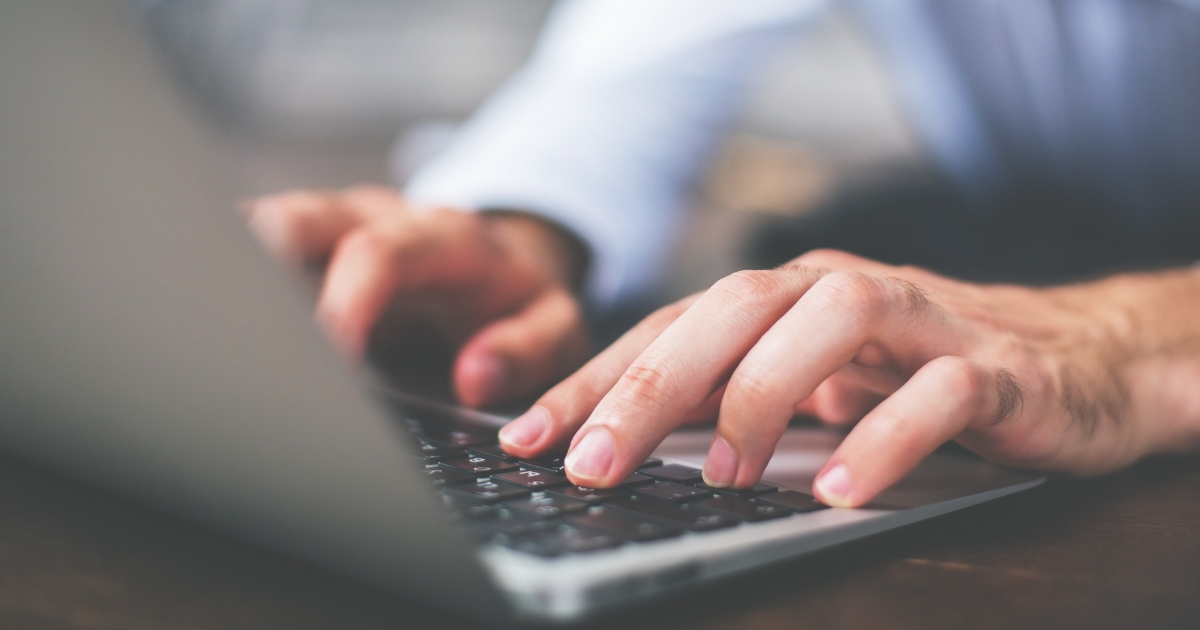 A man types on a laptop keyboard.