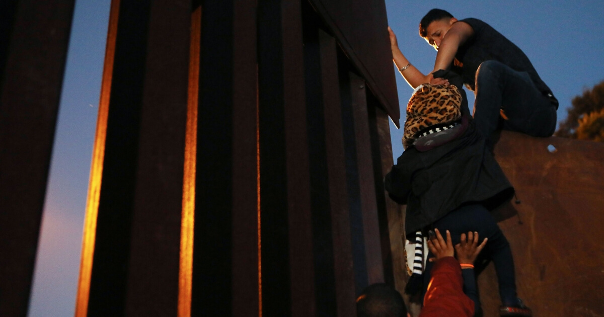 Illegal immigrants climb over the U.S.-Mexico border fence in Tijuana, Mexico, on Monday.