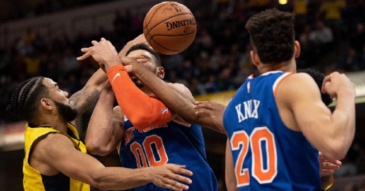 Basketball players battle for an aloft ball.