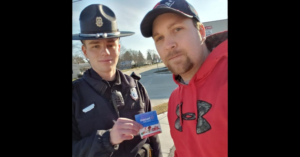 A state trooper gives a man two gift cards.