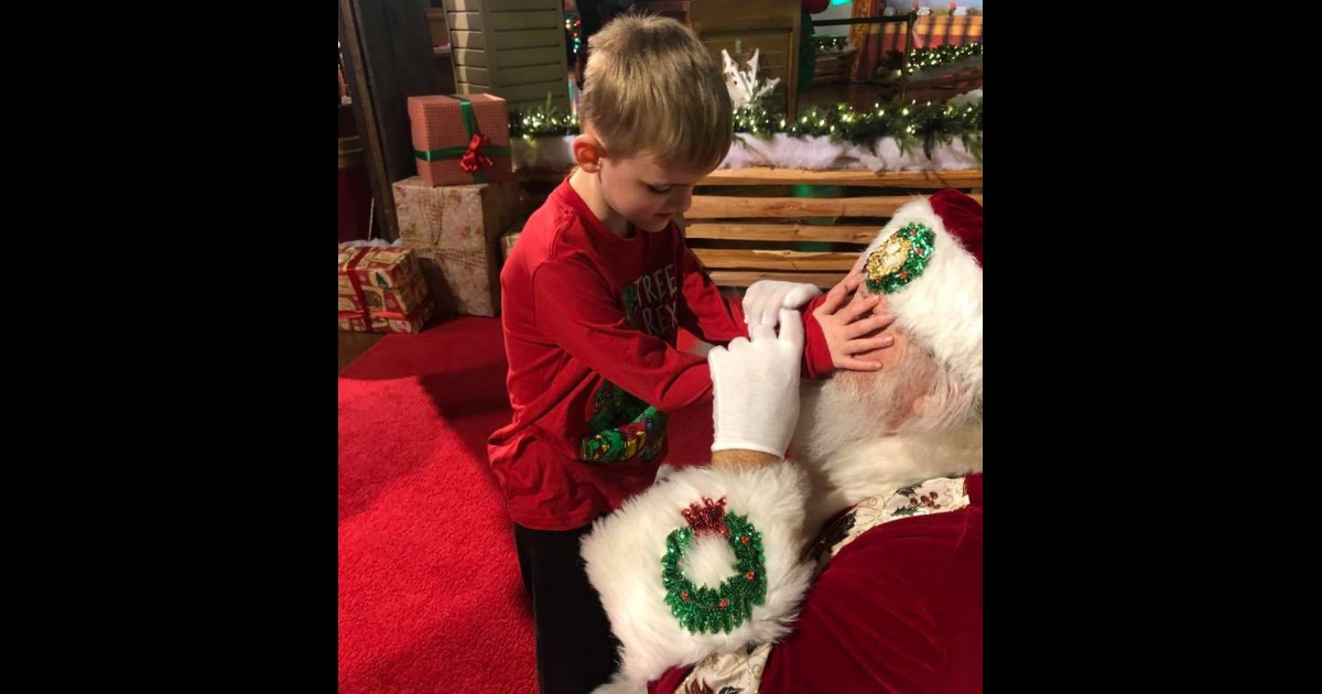 Blind boy with Autism touches Santa Claus' face.