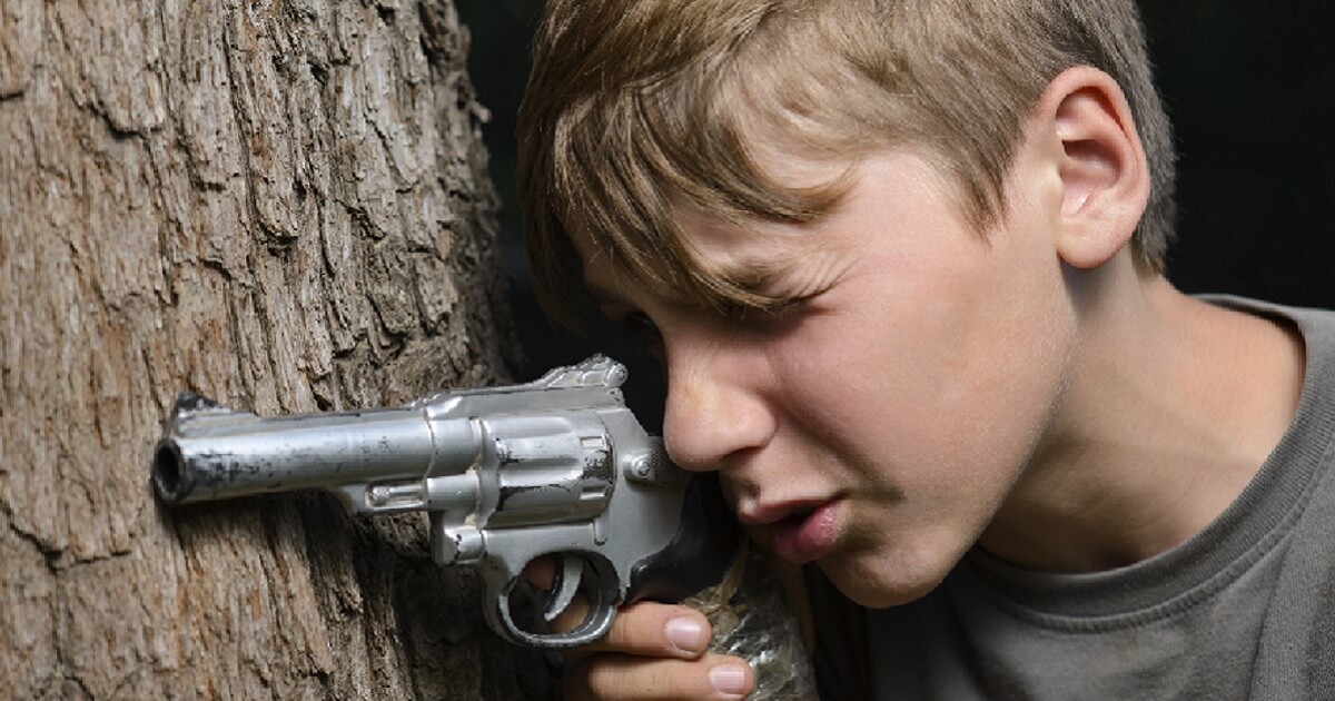 Little boy aiming toy gun.