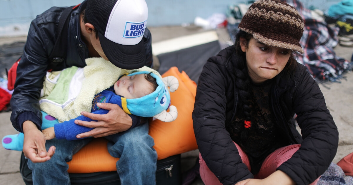 Honduran father Alexandre holds his son Karmaliel, who is sick with a fever,