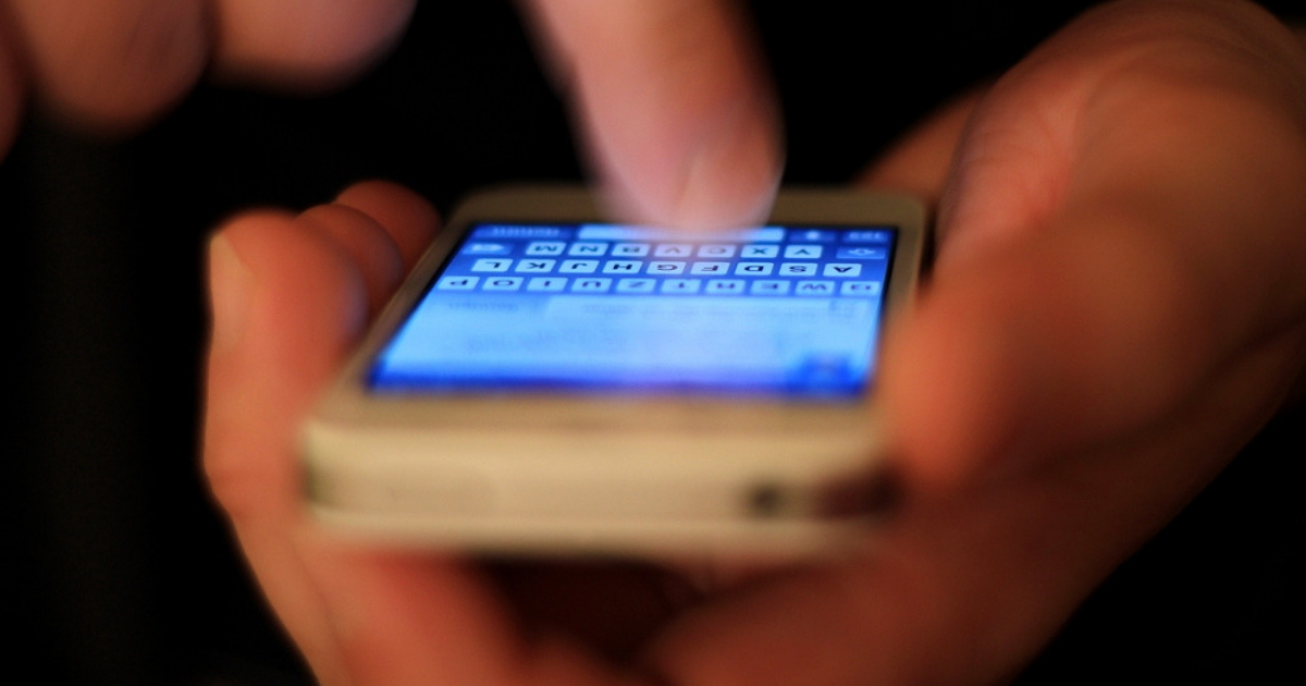 A person uses a cell phone to send a text message
