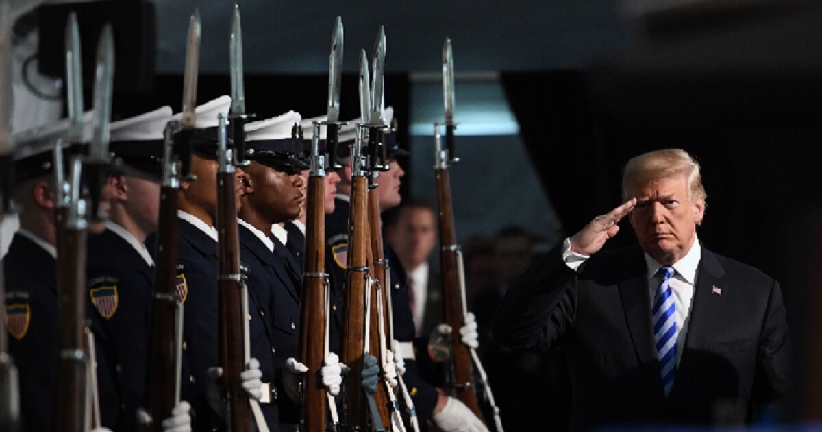 Trump salutes line of Coast Guardsmen presenting arms.