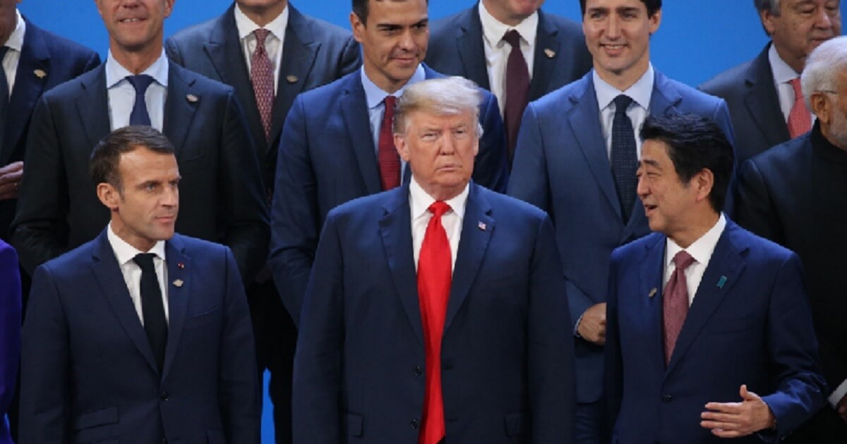 President Donald Trump stands between French Preisident Emmanuel Macron, left, and Japanese Prime Minister Shinzo Abe on Friday during a group picture shoot at the G-20 economic summit in Buenos Aries, Argentina.