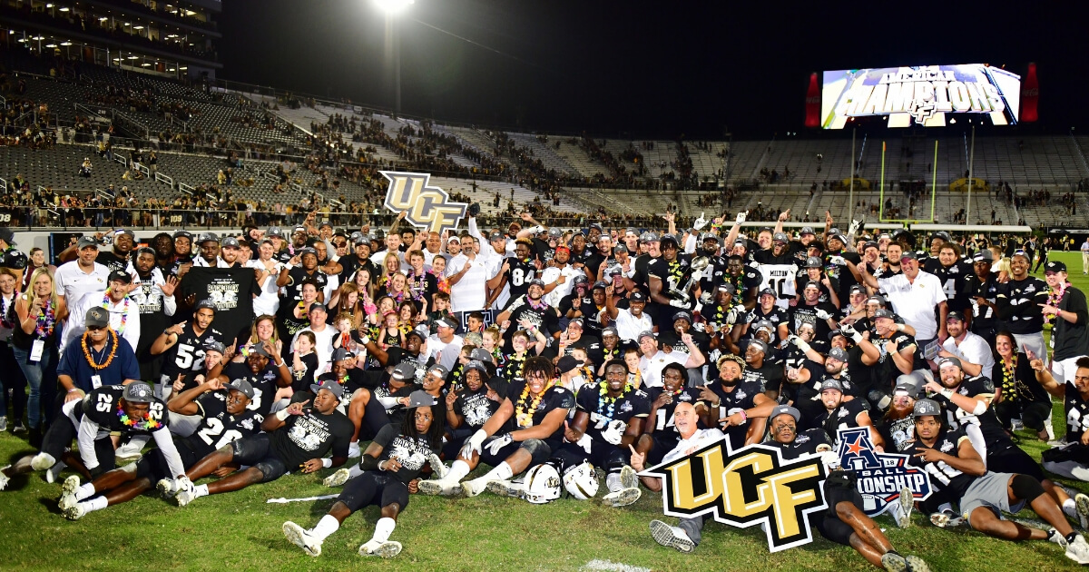 The UCF Knights celebrate with the American Athletic Conference trophy after defeating the Memphis Tigers 56-41 in the American Athletic Championship on Saturday at Spectrum Stadium in Orlando.