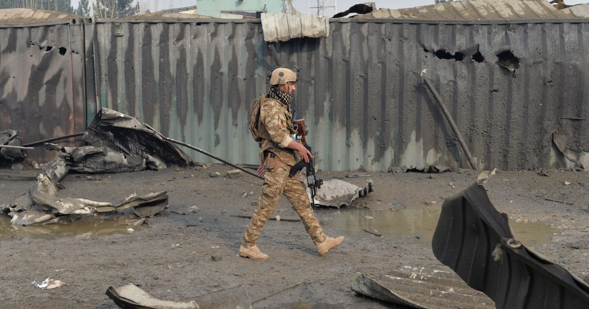 A member of the Afghan security forces walks at the site of a suicide bomb attack outside a British security firm's compound in Kabul.