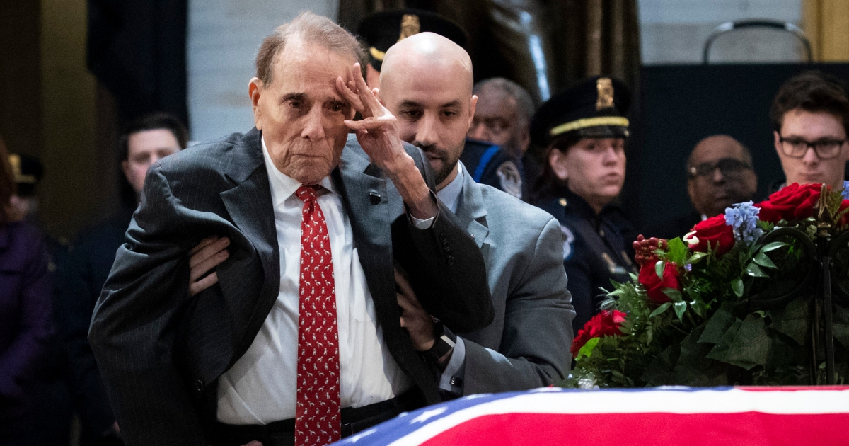 Former Senator Bob Dole stands up and salutes the casket of the late former President George H.W. Bush as he lies in state at the U.S. Capitol.
