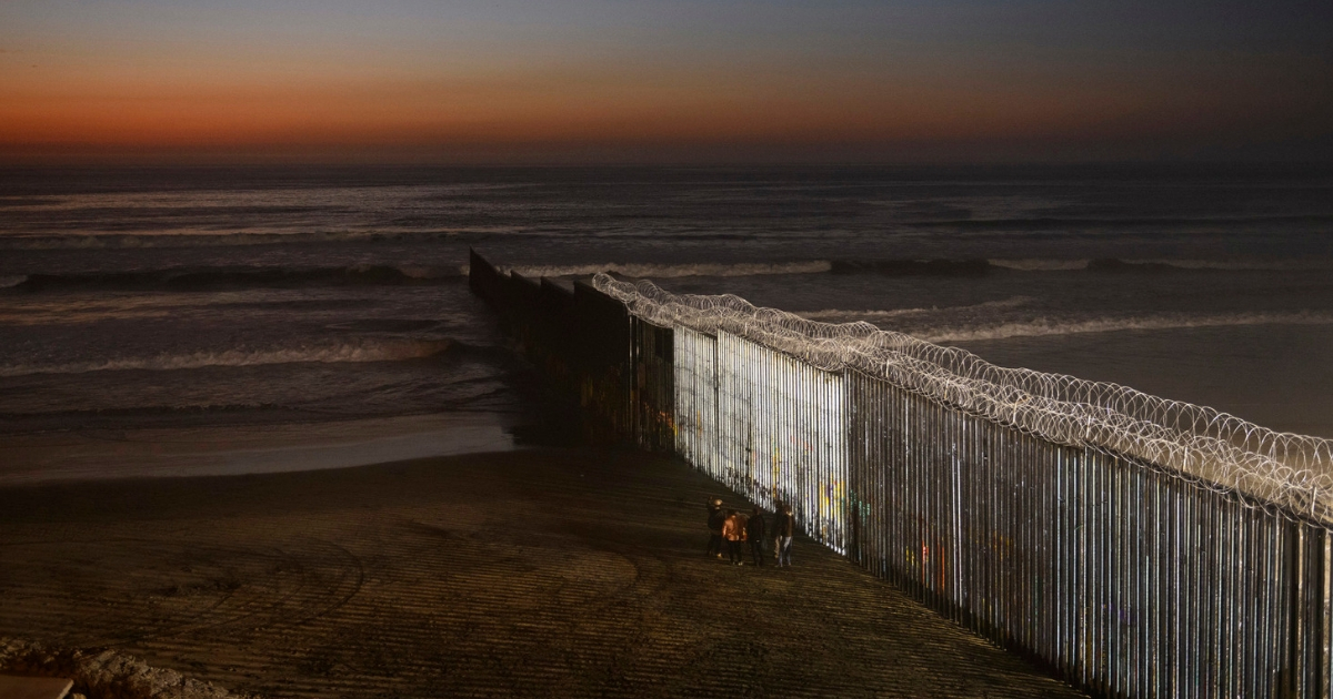 People stand by the border wall between Mexico and San Diego, California, as the sun sets at Playas de Tijuana, Mexico, Dec. 21, 2018.