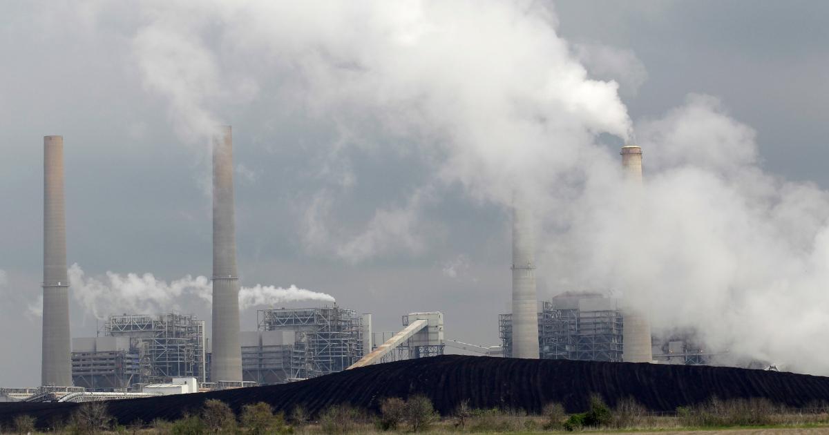 In this March 16, 2011, photo, exhaust rises from smokestacks in front of piles of coal at NRG Energy's W.A. Parish Electric Generating Station in Thompsons, Texas.