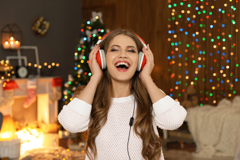 Happy young woman listening to Christmas music at home