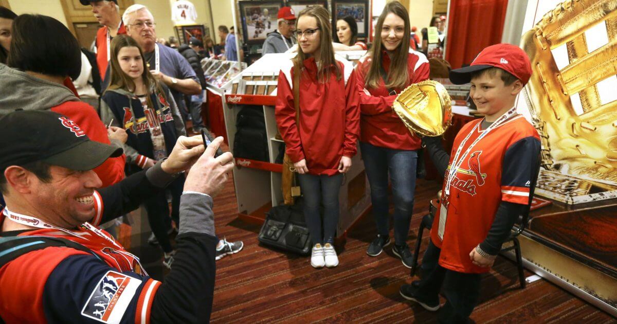 Maryland, snaps a photo of his son Caleb, 9, wearing St. Louis Cardinal catcher Yadier Molina's 2018 Golden Glove that was on display at the Cardinals Care Winter Warm-Up on Jan. 19, 2019, in St. Louis, Missouri.