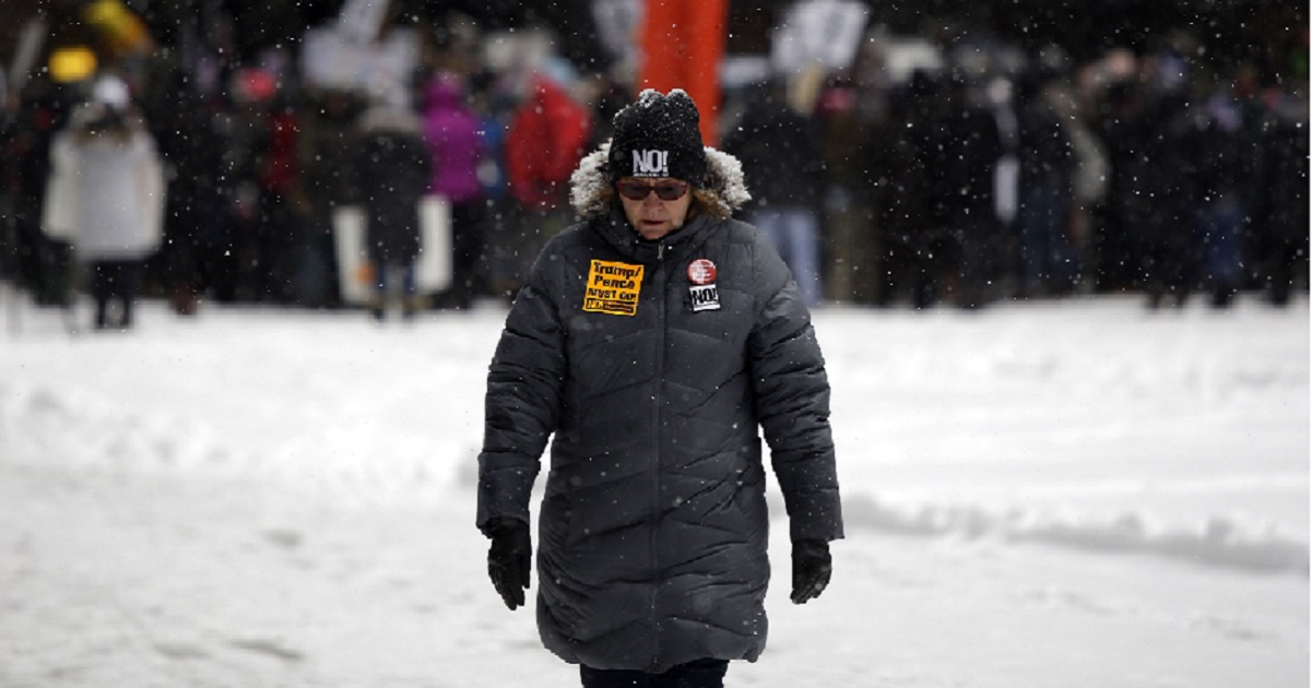 A woman walks through a snow-covered plaza.