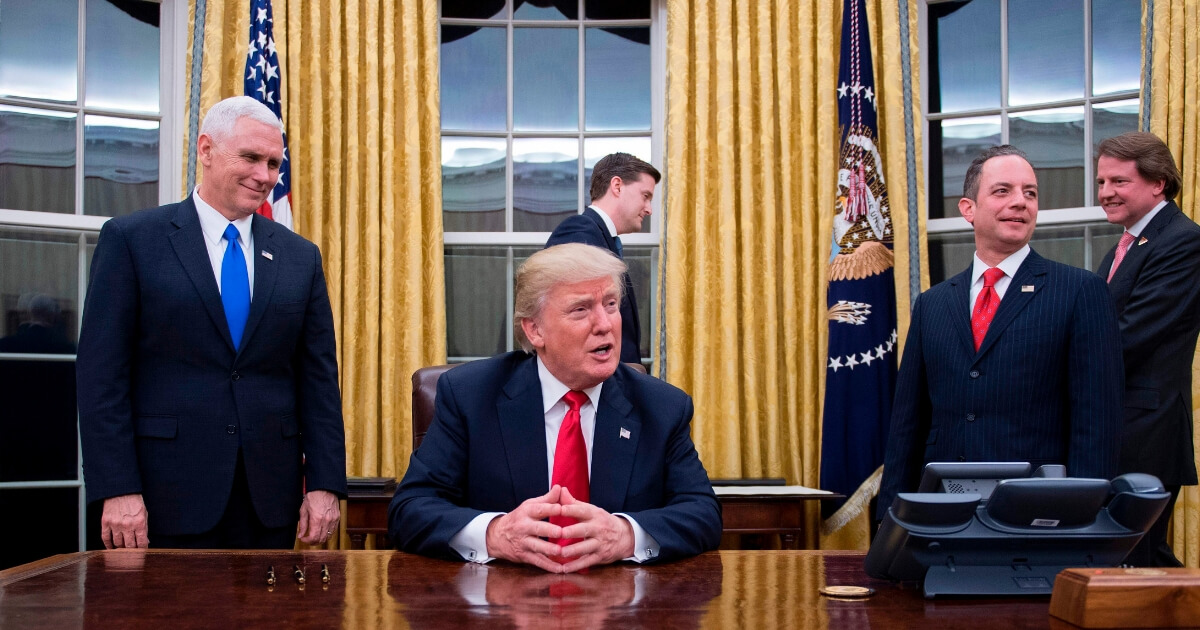 President Donald Trump (Center) speaks to the press as he waits at his desk before signing conformations on Jan. 20, 2017.