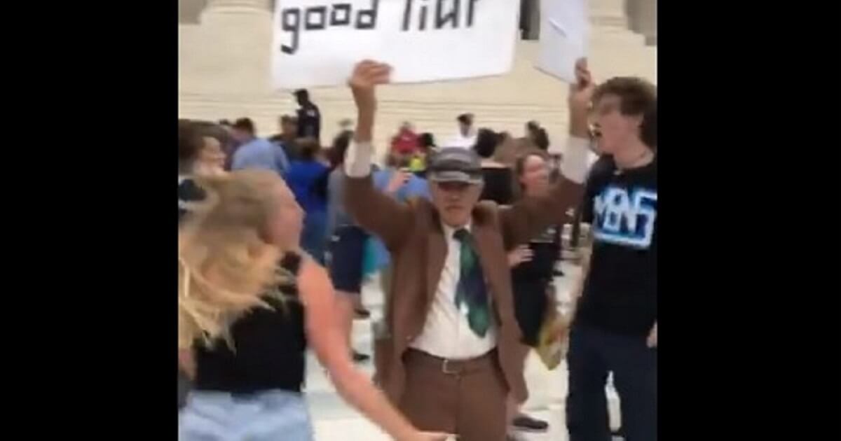 Demonstrators protesting the confirmation process for now-Supreme Court Justice Brett Kavanaugh dance aggressively around an elderly man supporting Kavanugh.
